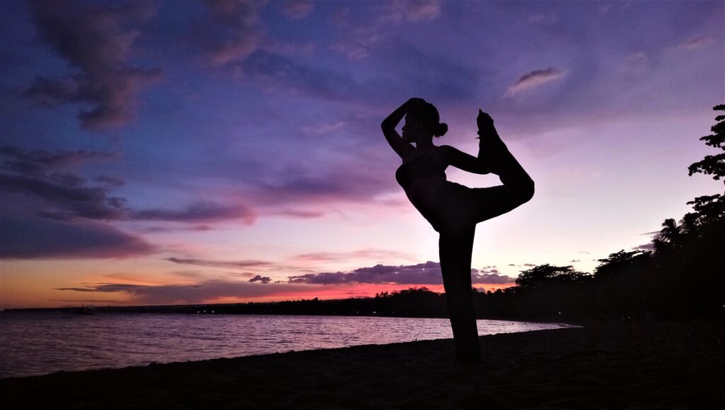 a woman doing yoga on the beach